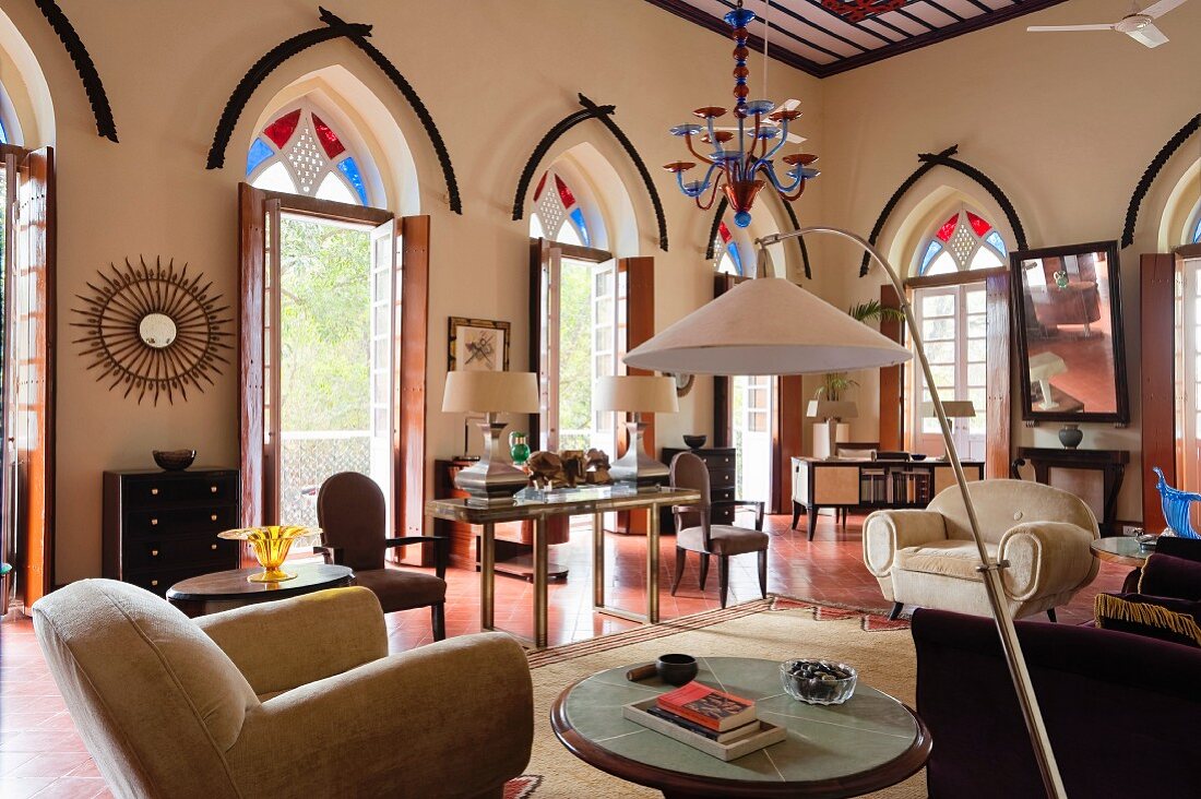 Indian residential house - elegant living room with modern standard lamp in lounge area, open terrace doors and coloured fanlights in pointed arches above