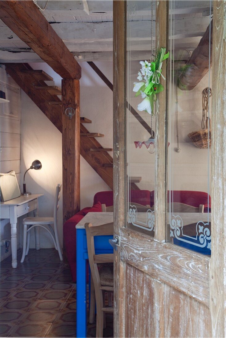 Offene Fenstertür im Shabby Stil öffnet den Blick in offenen Wohraum mit rustikalen Holzstützen und Fliesenboden