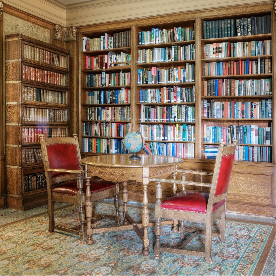 Historische Bibliothek mit antikem Tisch und Stühlen vor einer Bücherwand