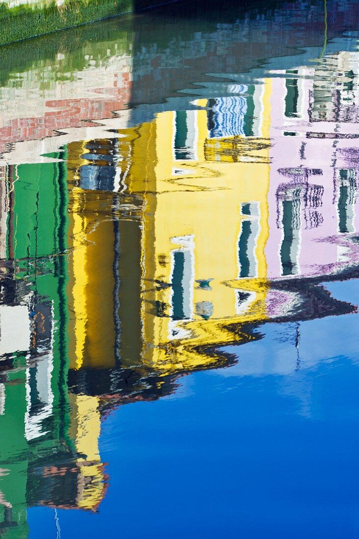 Historic homes in assorted colors reflected on the surface of the water in a canal