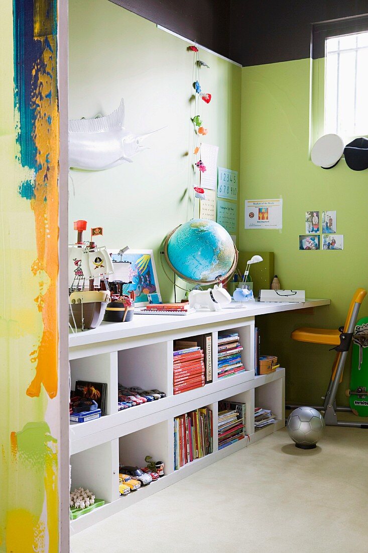 Blick durch offenen Durchgang auf Arbeitsecke mit weisser Schreibtischplatte auf Regal an grün getönter Wand
