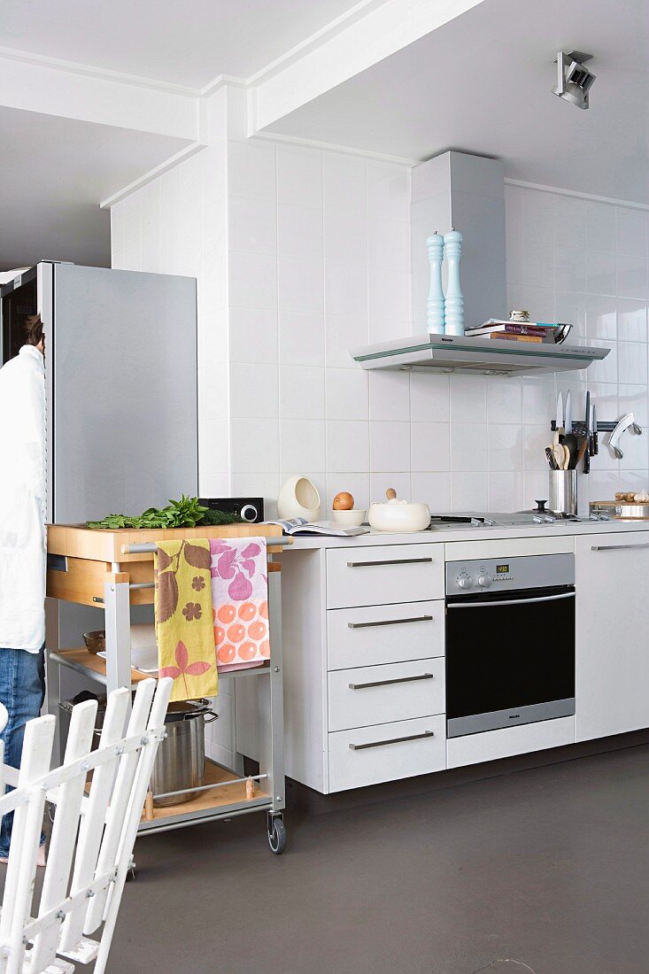 Rollbarer Schneidetisch neben moderner Küchenzeile mit Dunstabzug in loftartigem Raum