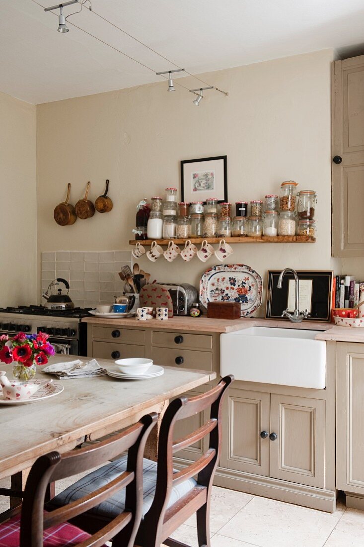 Dining area in front of kitchen counter below open spice shelf in English country-house kitchen