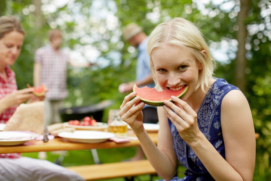 Frau isst Wassermelone beim Grillfest