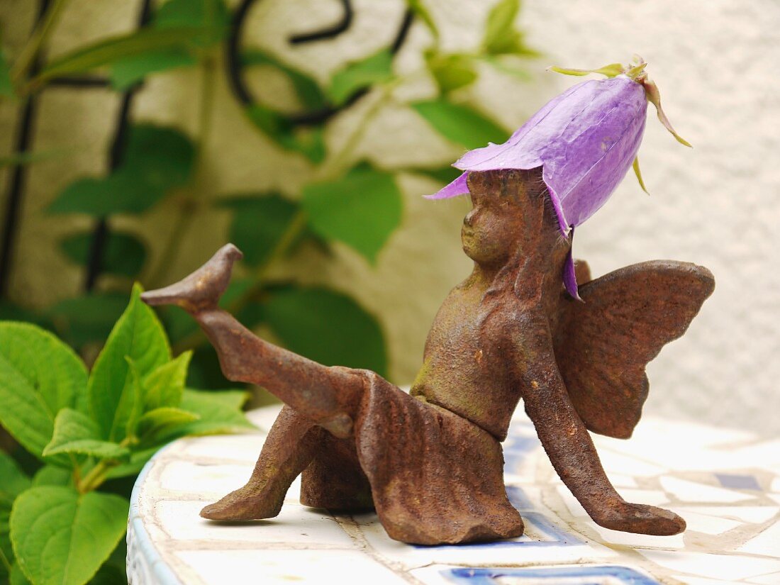 Small angel figurine with a flower hat in the gardne