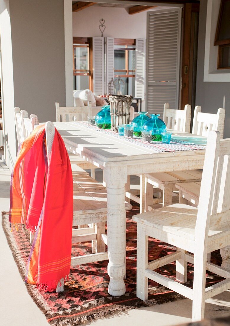 Rotes Tuch auf weiss lackiertem Holzstuhl und Tisch auf Terrasse