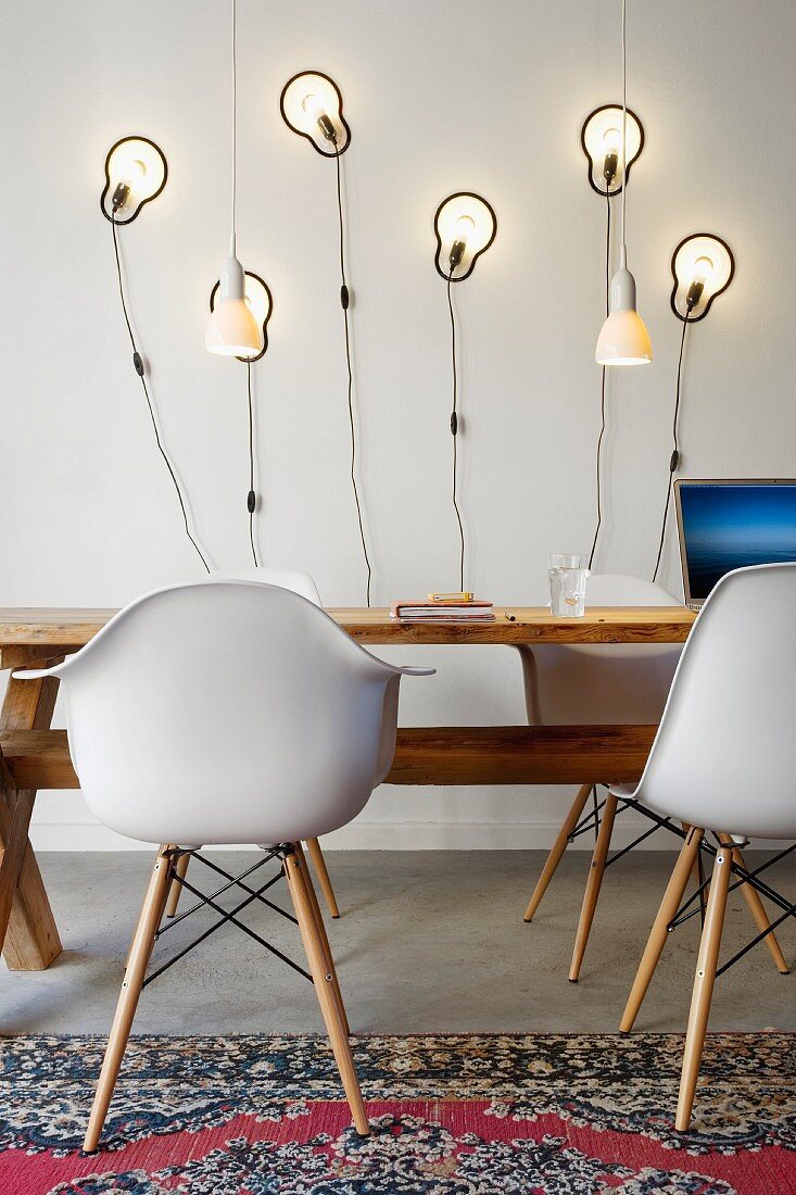 Bauhaus Schalenstühle an rustikalem Holztisch vor modernen Wandleuchten