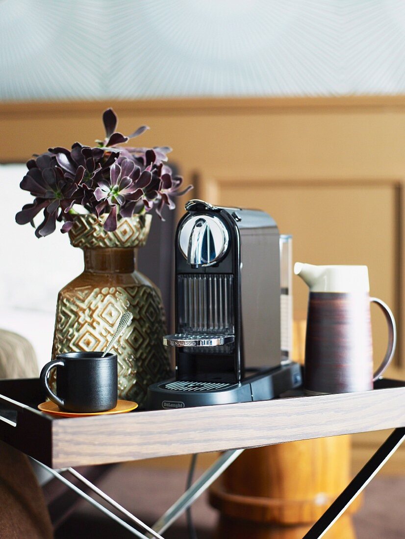 Modern coffee machine and retro vase of flowers on folding tray table