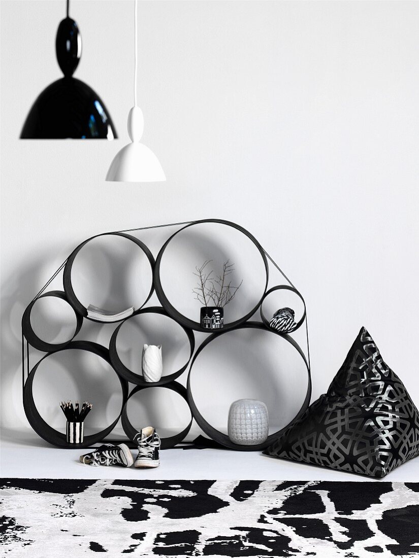 Shelves made from metal rings of various sizes bound together against wall and vintage pendant lamps with black and white lampshades