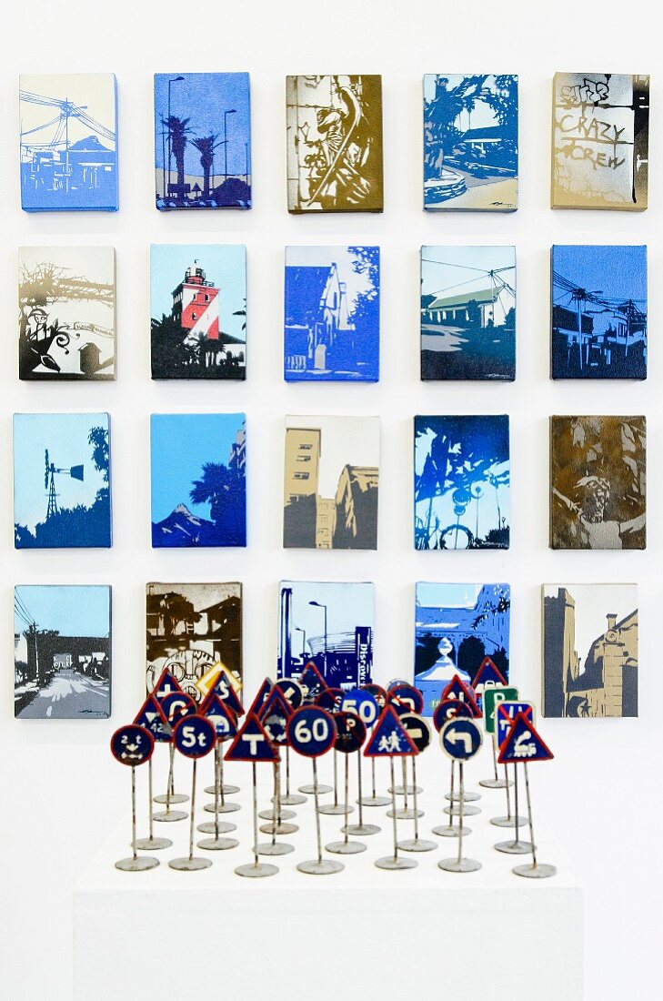 Vintage miniature traffic signs on white surface in front of artistically modified photos on wall