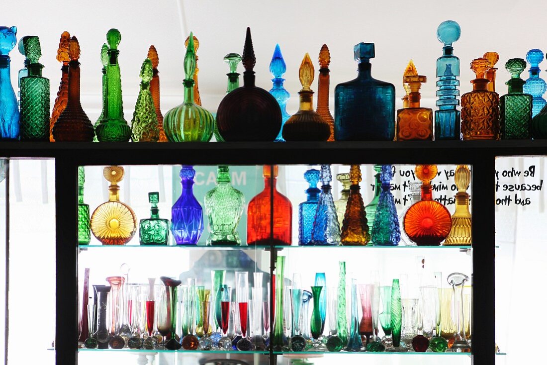 Pretty coloured glass bottles and vases on partition shelving