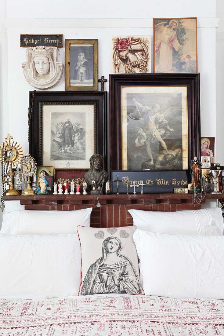 Religious pictures and statues around head of bed; scatter cushion printed with a Madonna and hearts