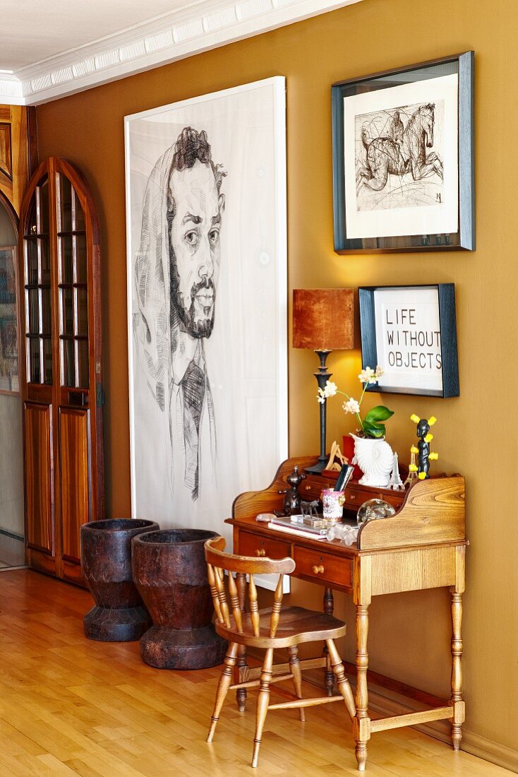 Kleiner Sekretär mit Holzstuhl neben grossformatigem Bild an ockerfarbener Wand im Flurbereich
