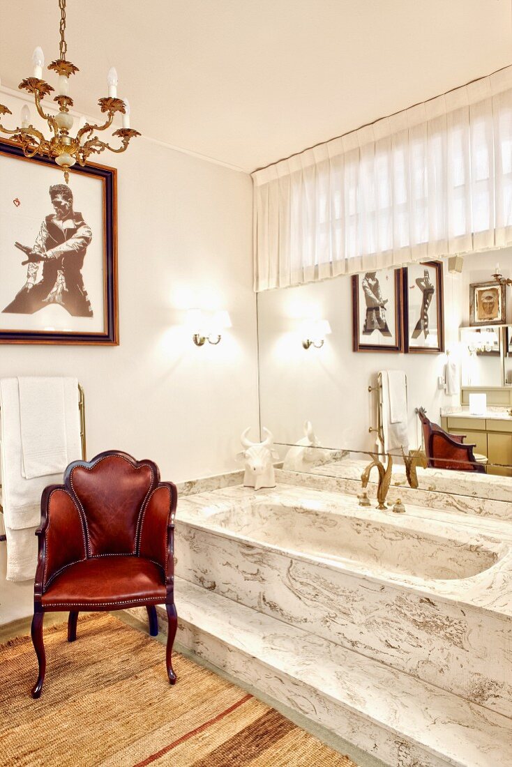 Vintage Lederstuhl neben Badewanne auf Empore mit Stufe aus marmorartigem Stein