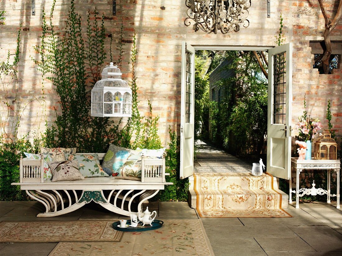 Rustic ambiance with antique bench, birdcage suspended from ceiling and open double doors with view of garden