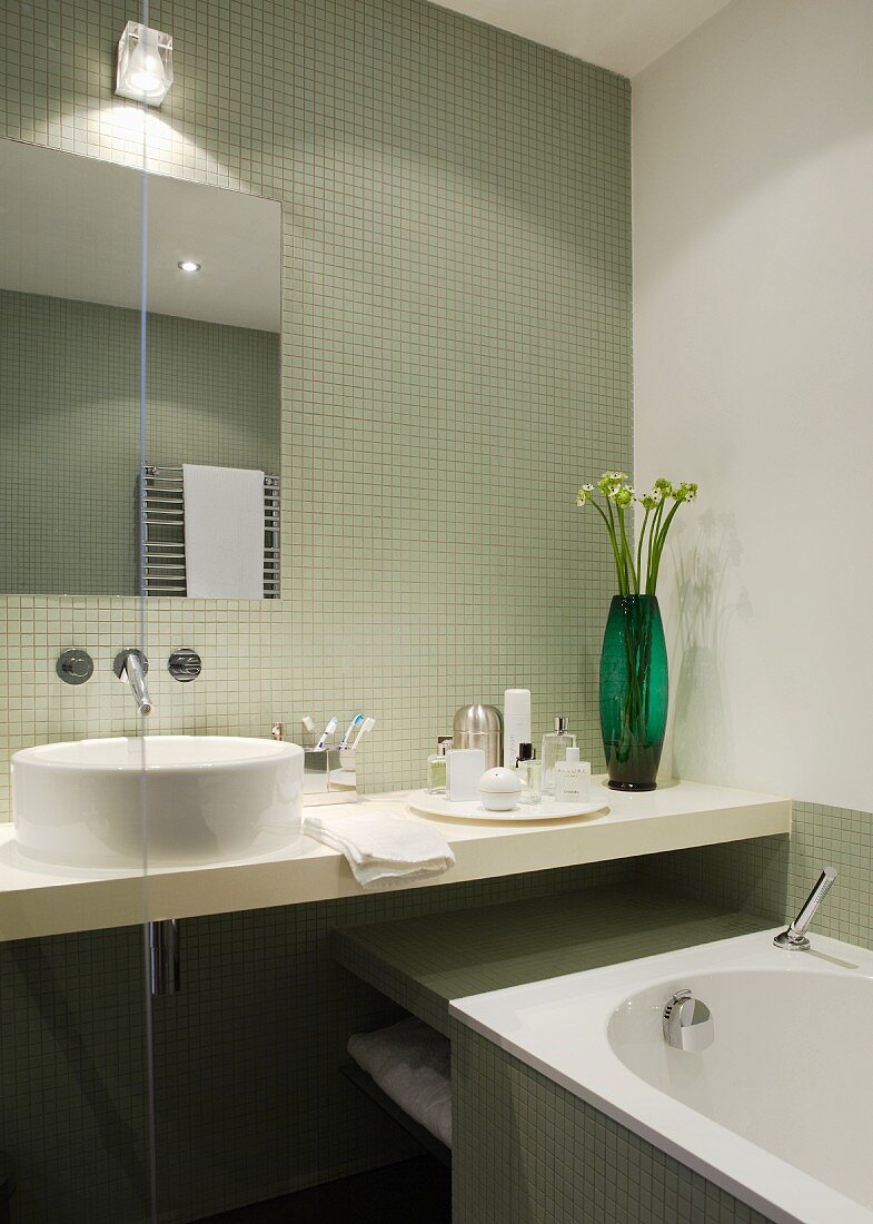 Blick auf den Waschtisch und Badewanne im Badezimmer mit pistaziengrünen Mosaikfliesen