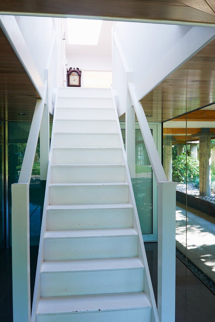 White wooden staircase with balustrades in entrance area of contemporary wooden house
