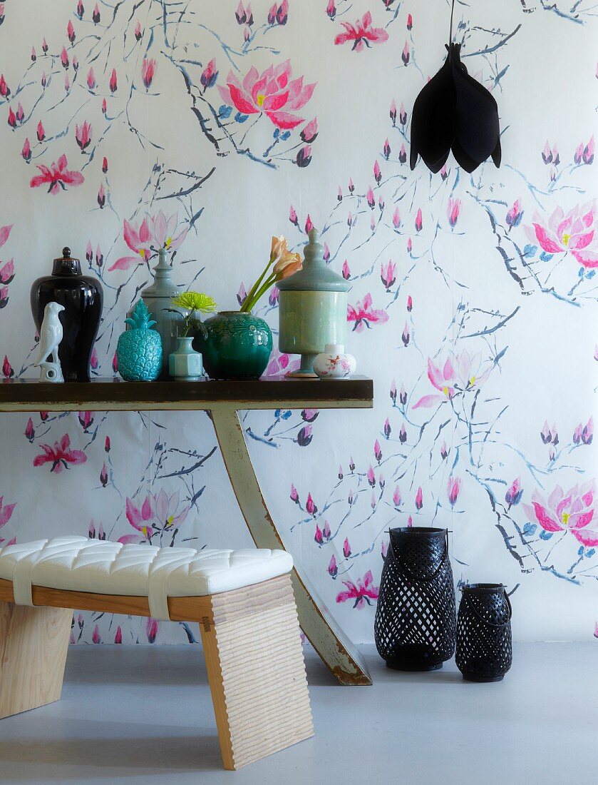 Wandtapete mit luftigem Magnolienmotiv; im Vordergrund ein Wandtisch mit chinesischen Vasen
