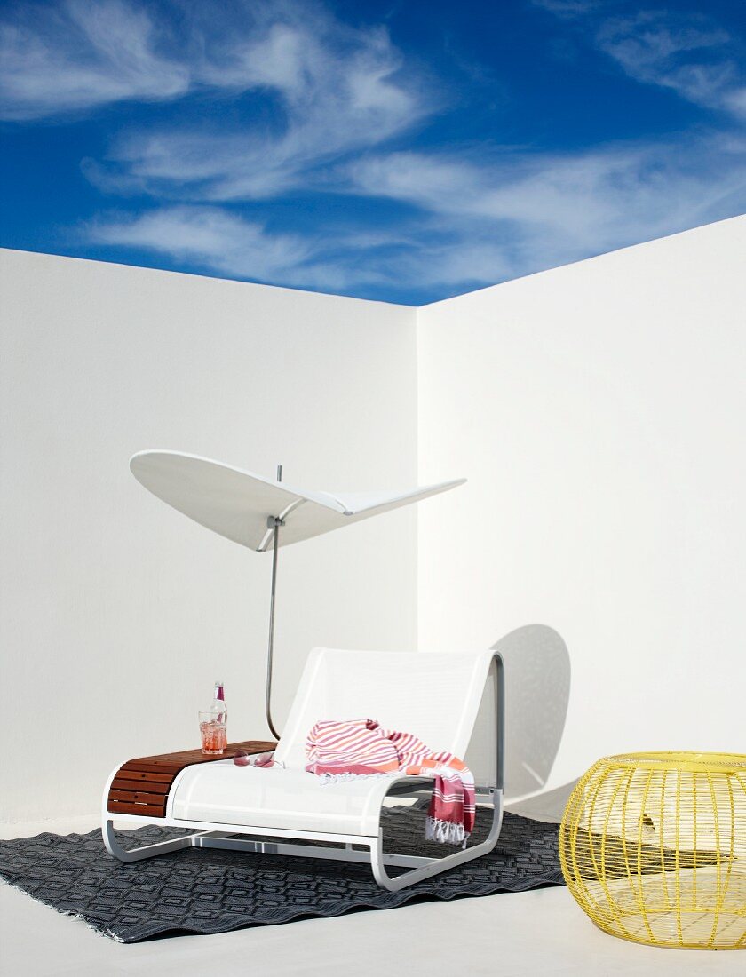 White, designer sun lounger with integrated parasol and shelf on terrace