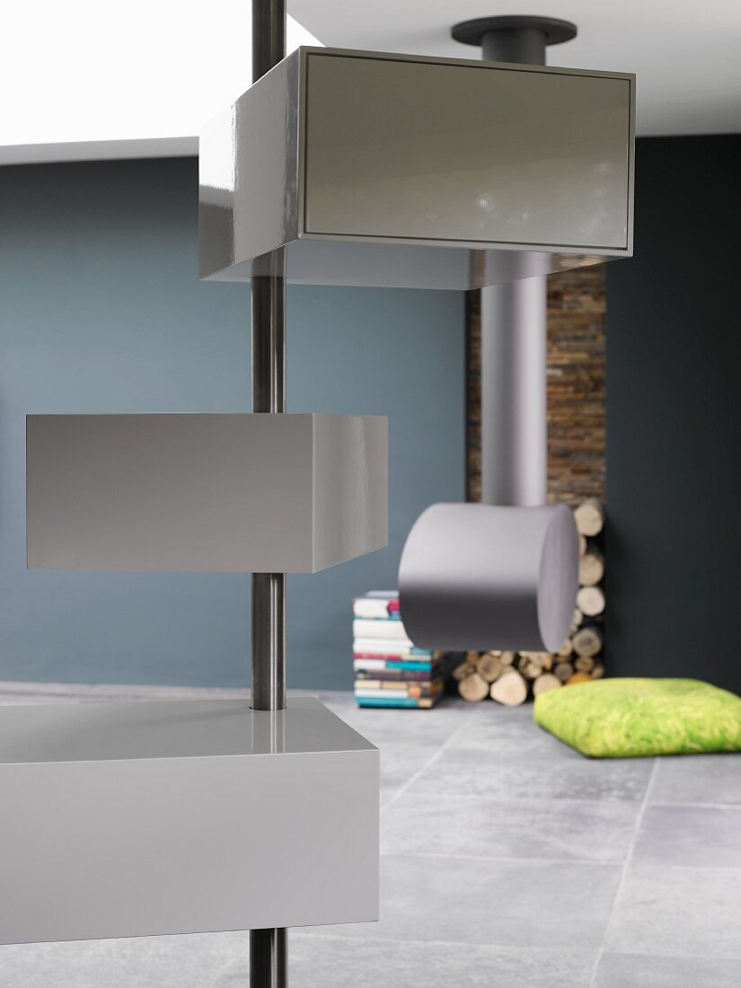 Designer interior with grey storage boxes on metal pole and modern fireplace in background