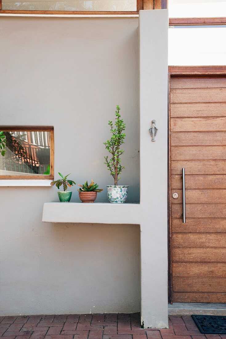 Hauseingangsbereich mit vorgezogener Wandscheibe und Stellfläche für Pflanzen