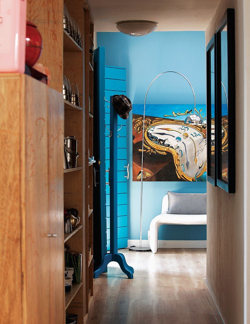 Schlichter Einbauschrank aus Holz im Flurbereich und surrealistisches Bild an blauer Wand