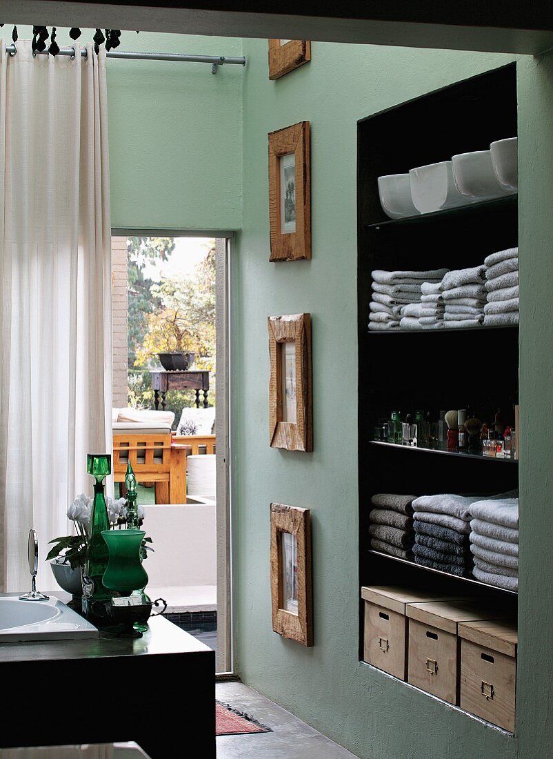 Blick über Waschtischecke auf Wandnische mit Handtüchern auf Regalen neben Terrassentür