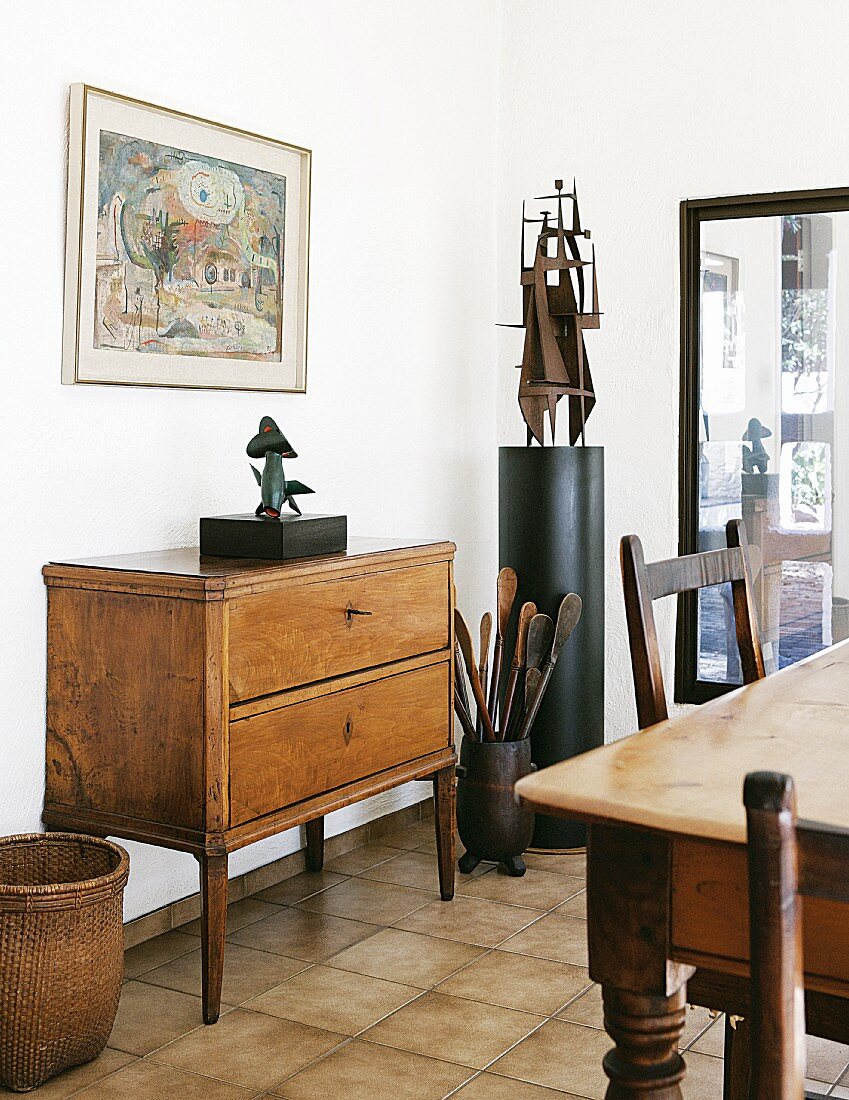 Chest of drawers with tall legs and ethnic objet d'art in contemporary dining room