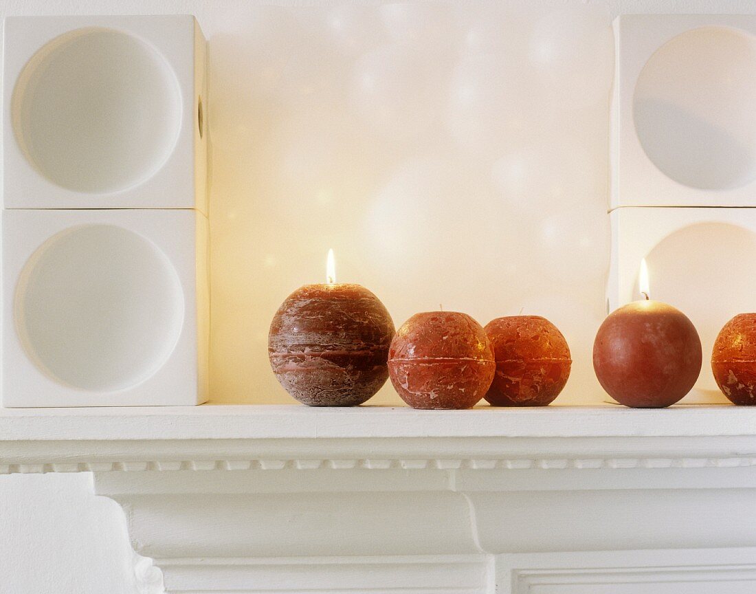 Lit sphere candles on mantelpiece
