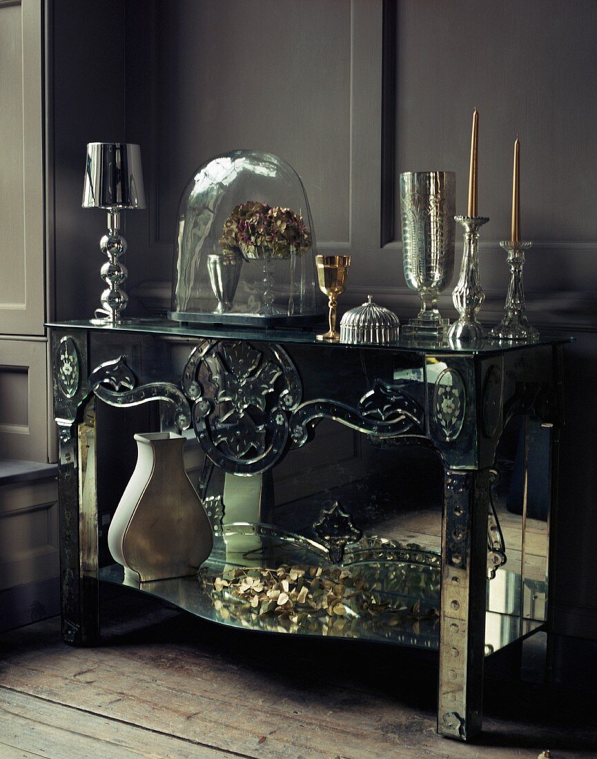 Corner of grey room with silver mirrored side table with ornaments