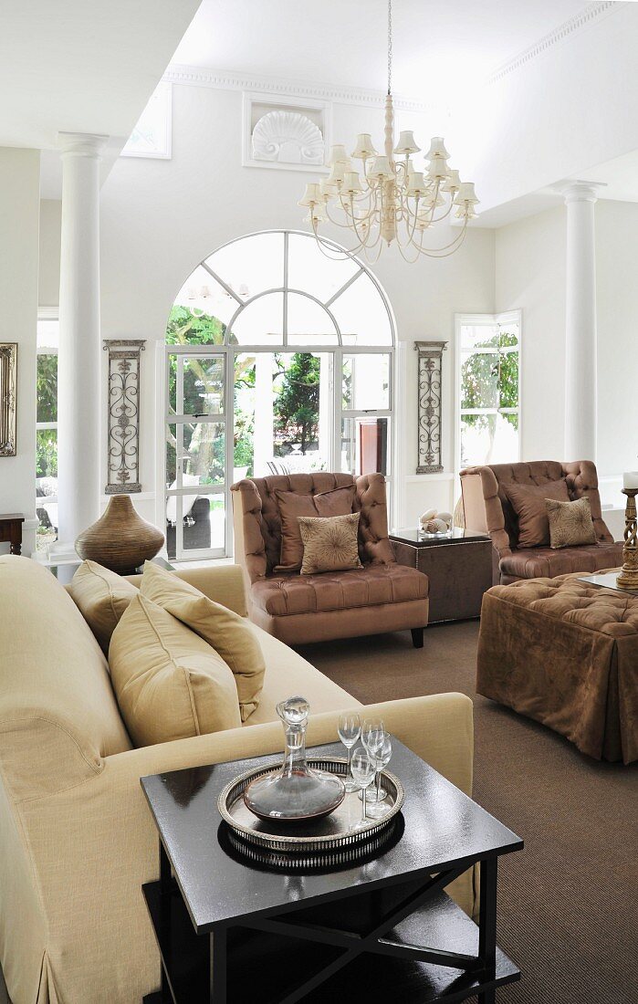 Exclusive living area with white columns, chandelier and elegant upholstered furnishings