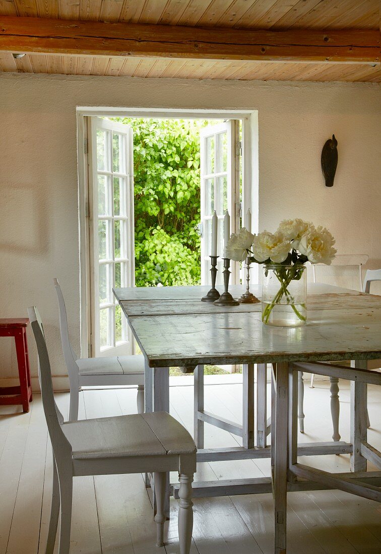 Weißer Holztisch mit Stühlen im Esszimmer mit weißen Dielenboden