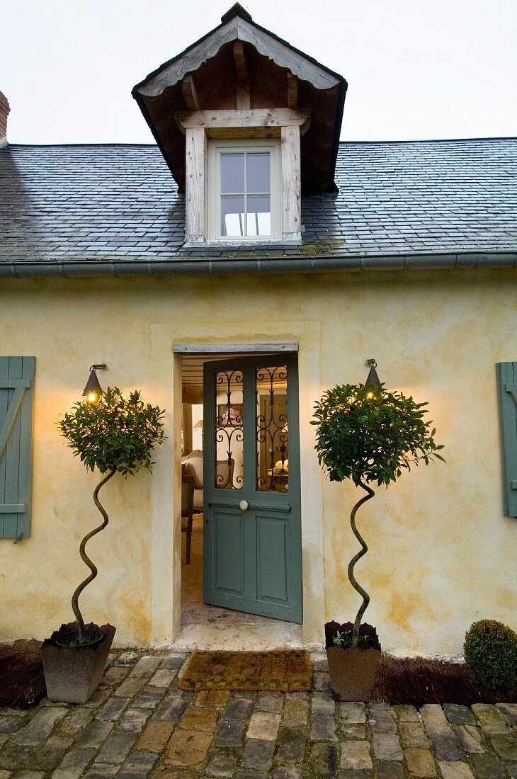 Einfaches, nordfranzösisches Landhaus mit Schieferdach, Dachgaube und mit eigenwilliger Pflanzendekoration neben der Eingangstür