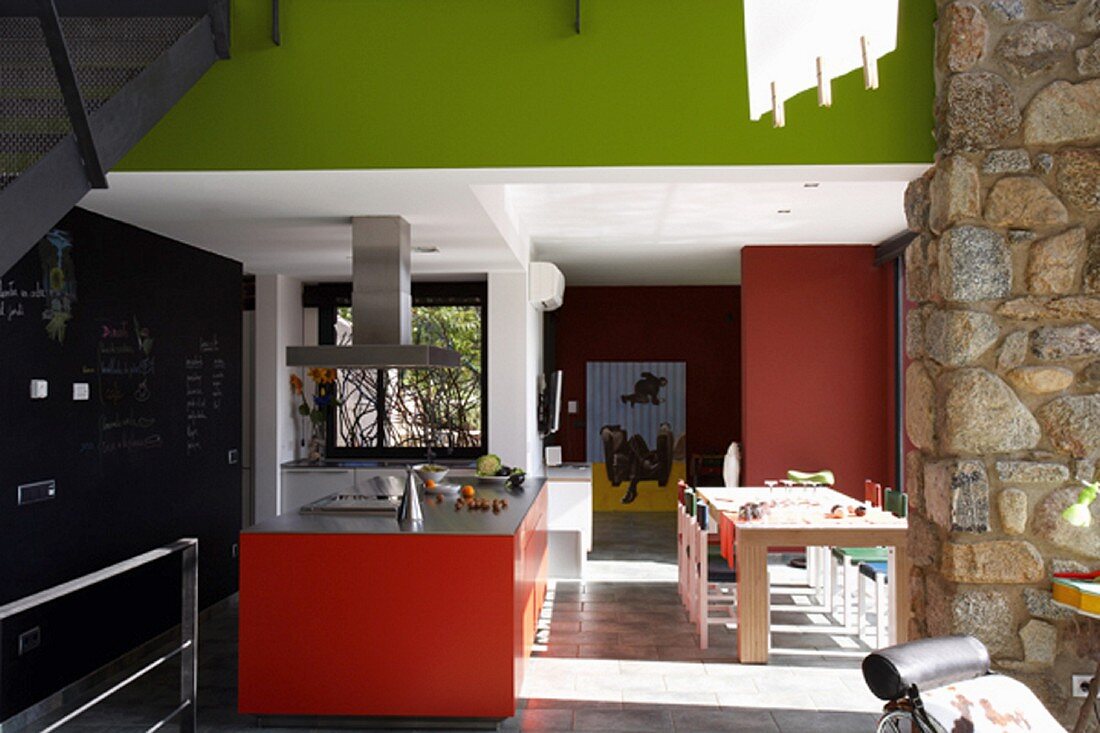 Moderne Küche mit farbigen Flächen in Rot und Frühlingsgrün im offenen Wohnraum