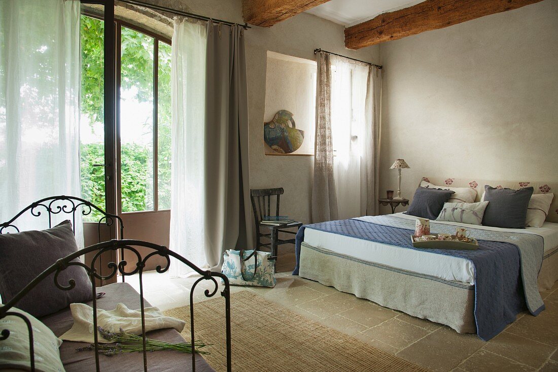 Doppelbett im rustikal eleganten Schlafzimmer eines französischen Landhauses