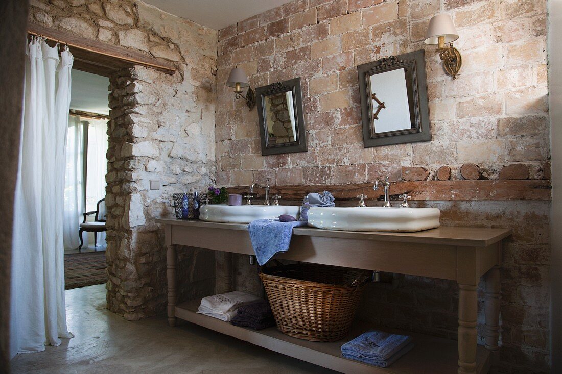 Waschtisch mit zwei Becken vor rustikaler Ziegelwand im Badezimmer eines provenzalischen Landhauses