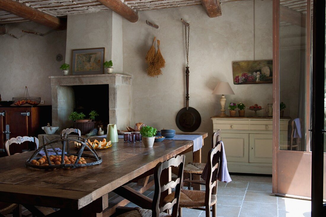 Stilvoller, rustikaler Essplatz vor gemauertem Kamin in der Küche eines restaurierten provenzalischen Landhauses