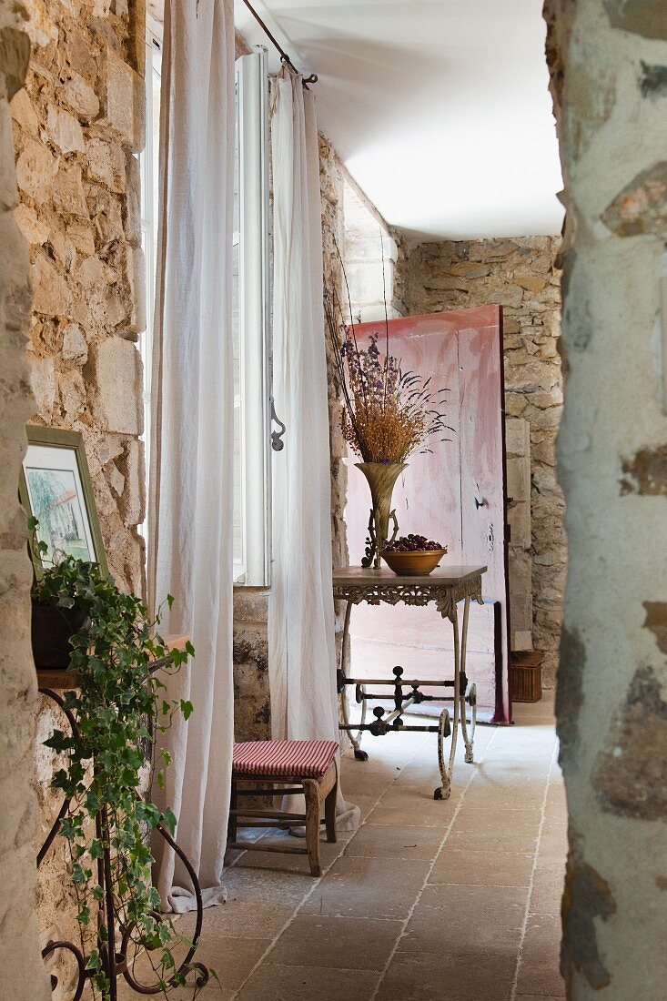 Zierliche, französische Metallmöbel vor den rustikalen Natusteinwänden eines provenzalischen Landhauses