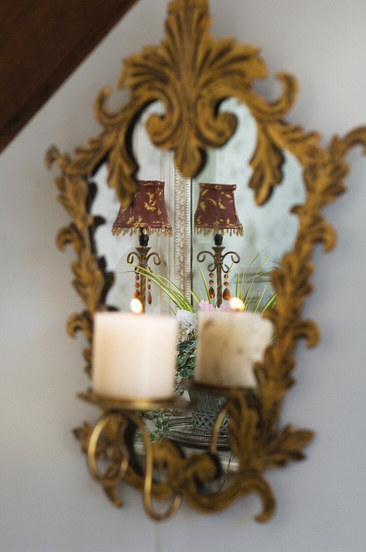 Verspiegelter Wandkerzenhalter mit brennender Kerze und vergoldetem Rahmen