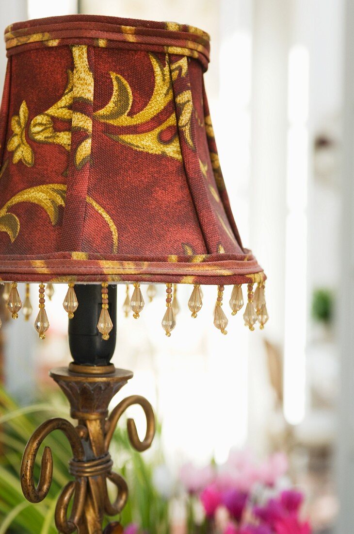 Tischlampe mit rot-goldenem Lampenschirm und Perlendekoration