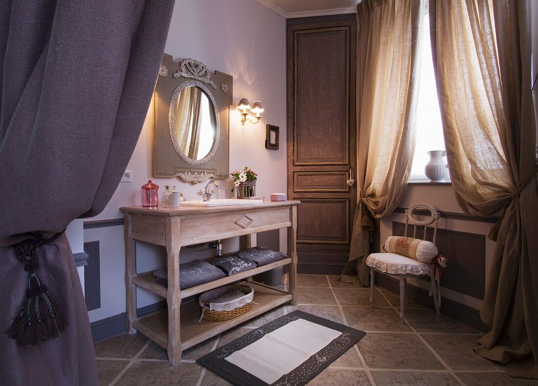 Spacious bathroom with heavy, gathered curtains and long, wooden washstand