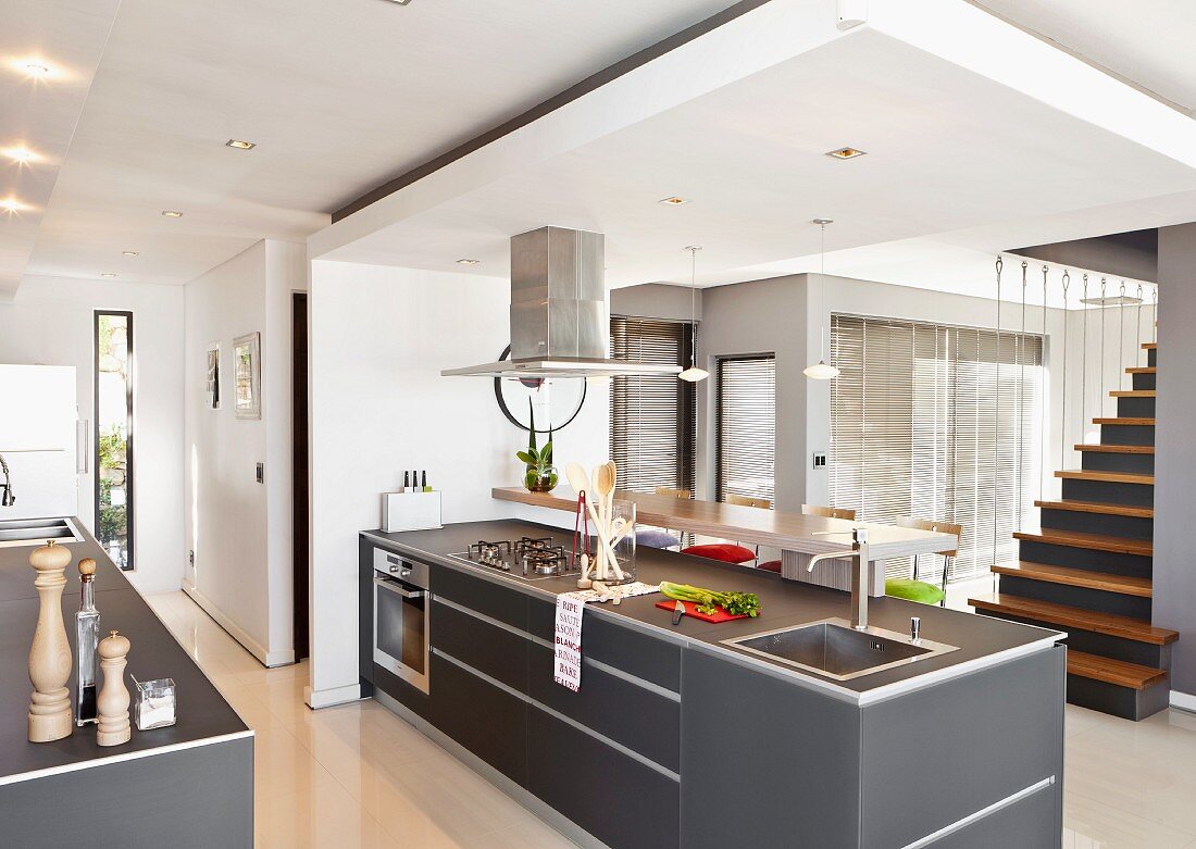 Freistehende Küchentheke mit grauen Oberflächen unter abgehängter Decke in modernem, offenem Wohnraum mit Treppenaufgang