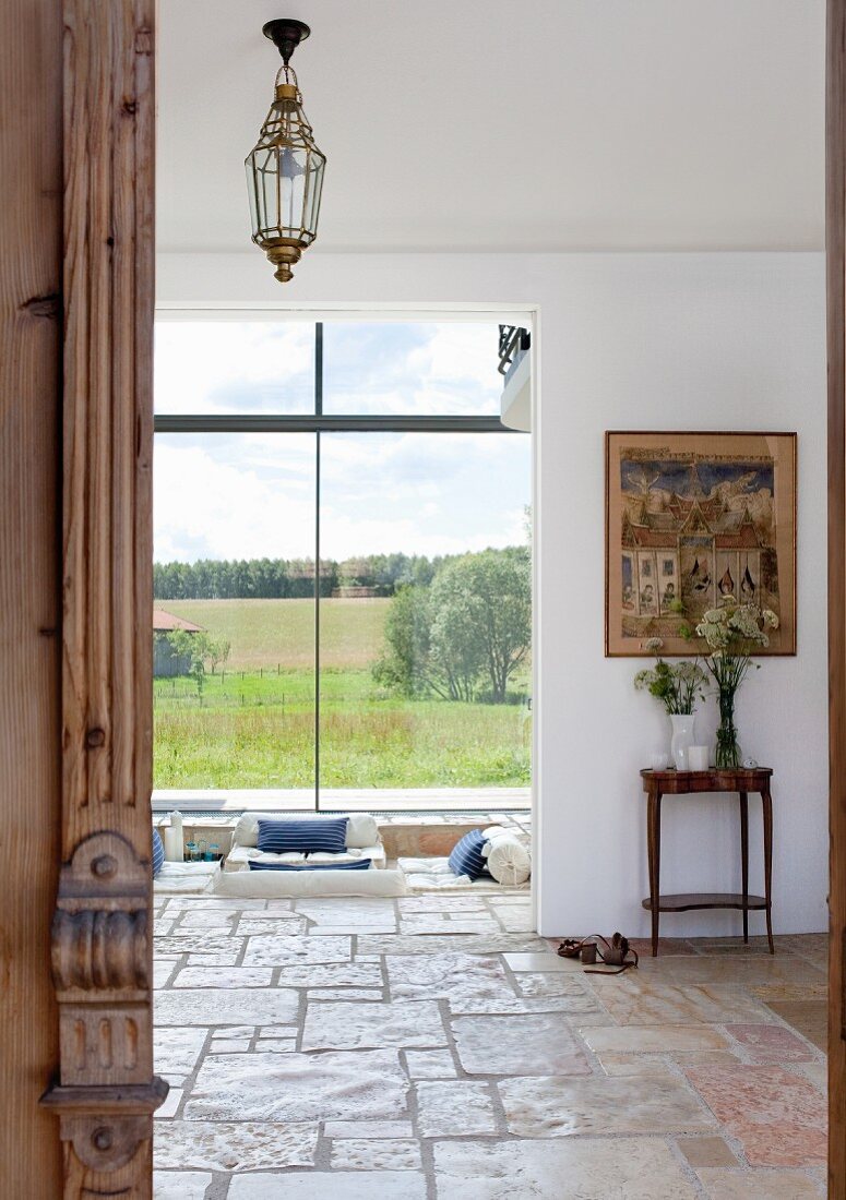 Blick in den Wohnbereich eines Einfamilienhauses mit rustikalem Steinboden und großen Panoramafenstern