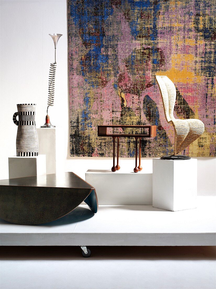 Designer-Möbelstücke auf Podest: Keramikgefäss, Lampe, Couchtisch, Beistelltisch und Stuhl