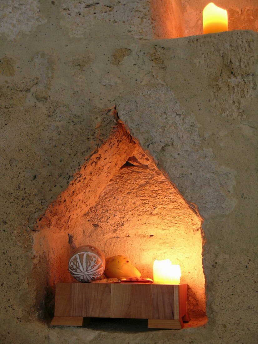 Spitz zulaufende Nische mit Kerzen in historischem Sandsteingemäuer
