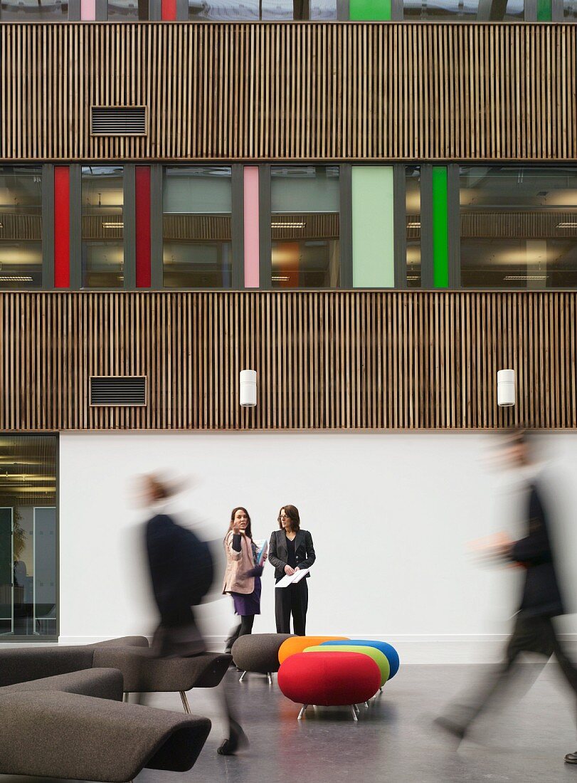 Stools with colourful upholstery in foyer of modern school building
