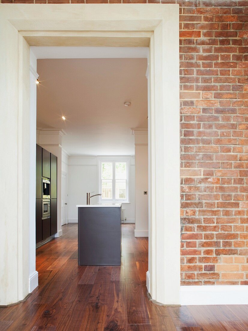 Brick wall with open doorway and view of free-standing kitchen counter