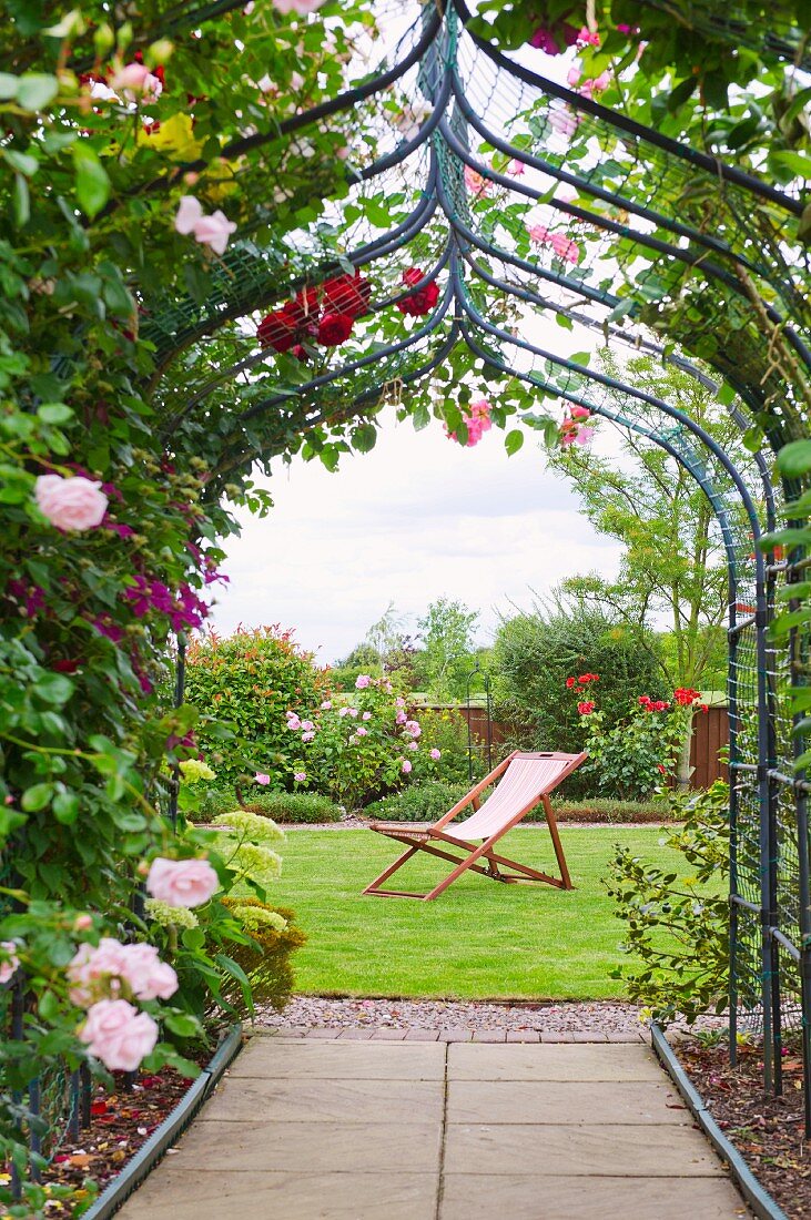 Blühender Rosenbogen in sommerlichem Garten