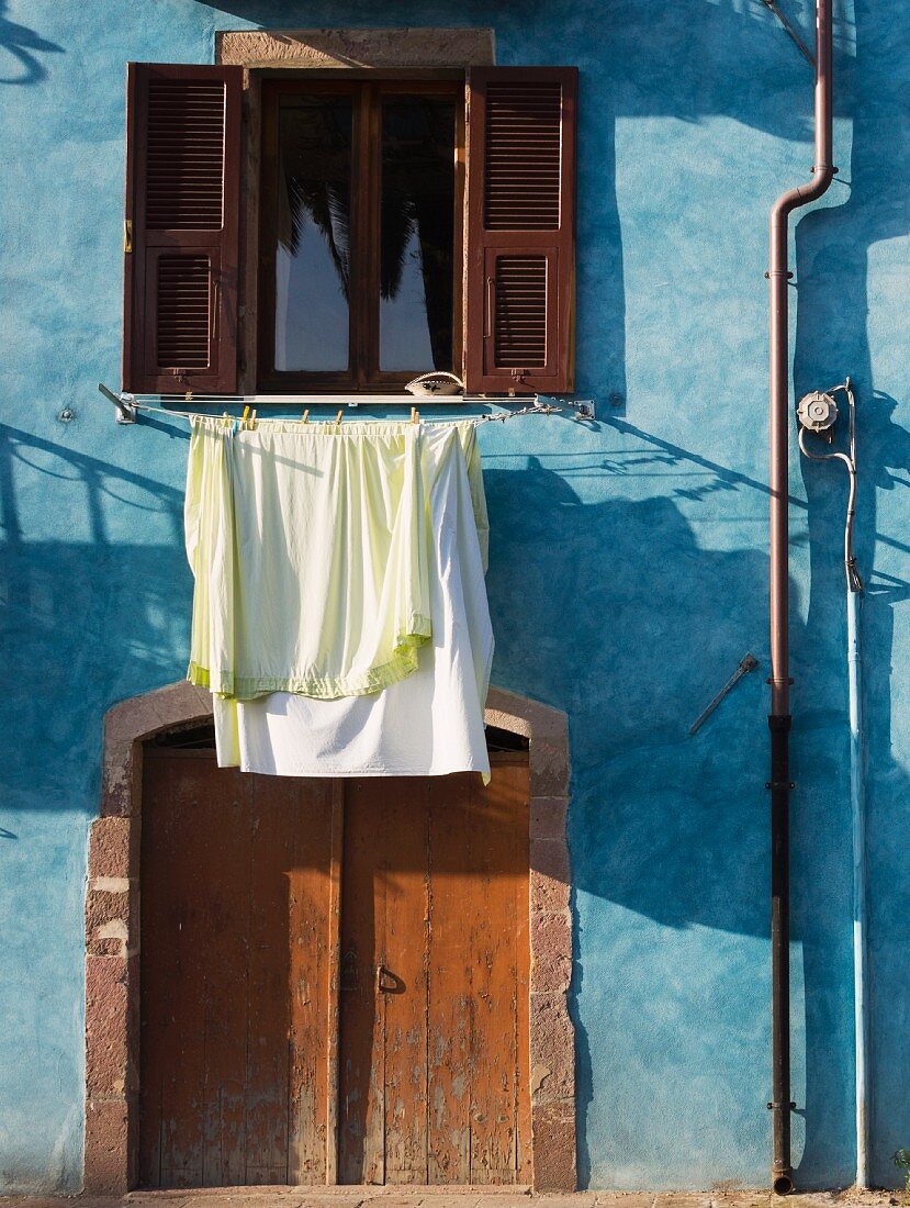 Pastel blue facade of Sardinian house with laundry hung out to dry