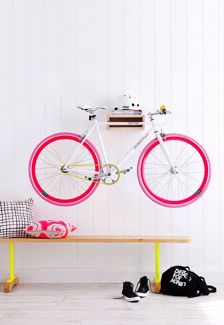 Bicycle hung on hall wall above a bench
